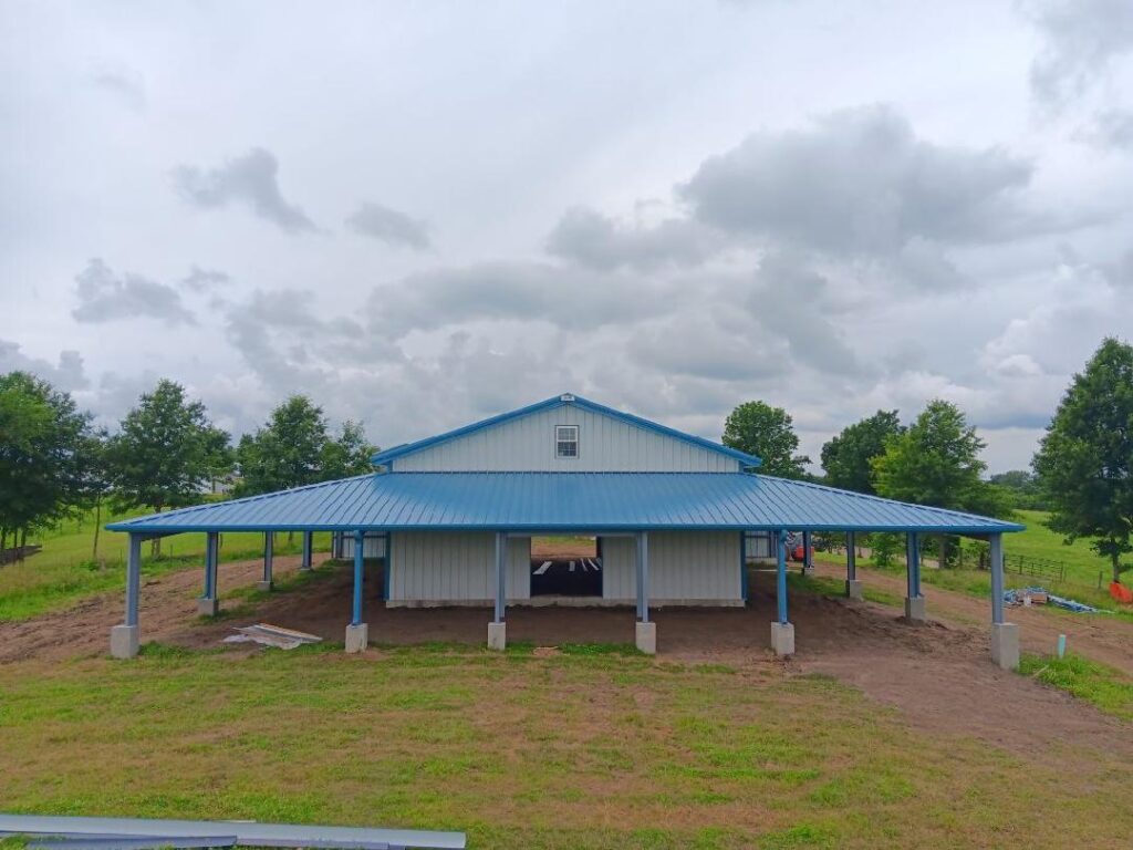 This 80'x80' steel building includes a wrapped 20' canopy porch on three sides. The main building has an 18" overhang and soffit on each side with gutters & downspouts. There is a 14'x14' slider door on the back side, 8'x8' opening on the other end, (6) 4x8 sidewall openings for individual horse stalls, a small window on each end and one 3070 walk door. The barn colors are Hawaiian Blue roof & trims with Polar White walls.