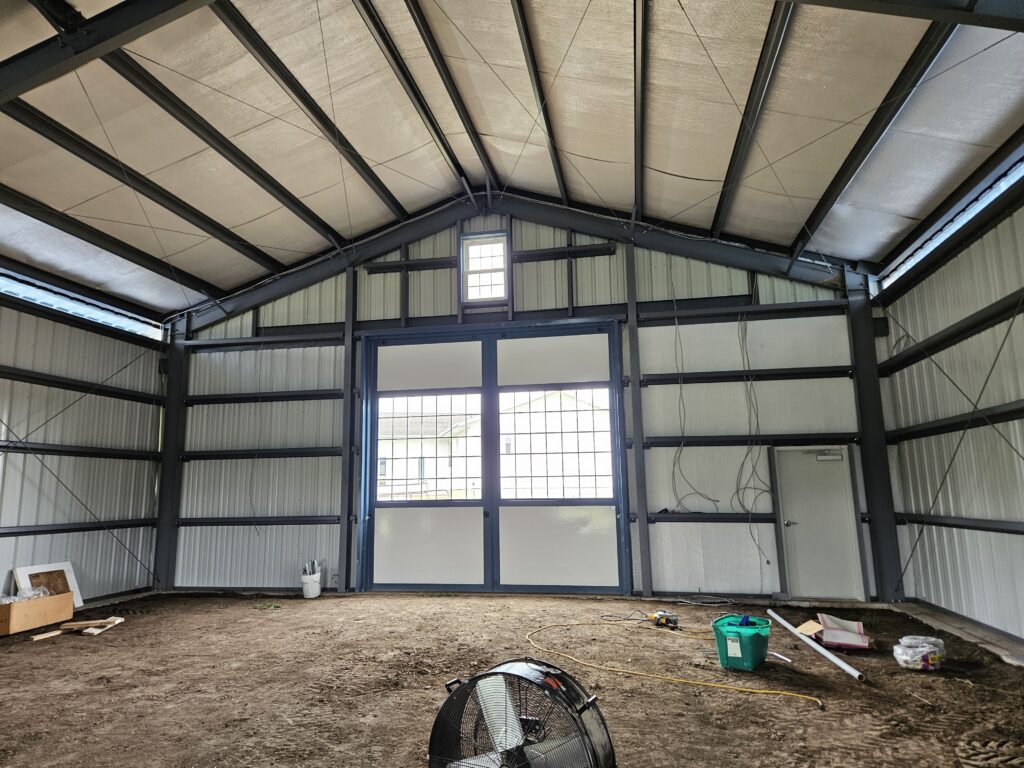 This 80'x80' steel building includes a wrapped 20' canopy porch on three sides. The main building has an 18" overhang and soffit on each side with gutters & downspouts. There is a 14'x14' slider door on the back side, 8'x8' opening on the other end, (6) 4x8 sidewall openings for individual horse stalls, a small window on each end and one 3070 walk door. The barn colors are Hawaiian Blue roof & trims with Polar White walls.