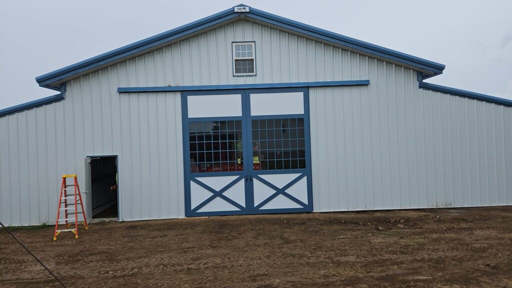 This 80'x80' steel building includes a wrapped 20' canopy porch on three sides. The main building has an 18" overhang and soffit on each side with gutters & downspouts. There is a 14'x14' slider door on the back side, 8'x8' opening on the other end, (6) 4x8 sidewall openings for individual horse stalls, a small window on each end and one 3070 walk door. The barn colors are Hawaiian Blue roof & trims with Polar White walls.